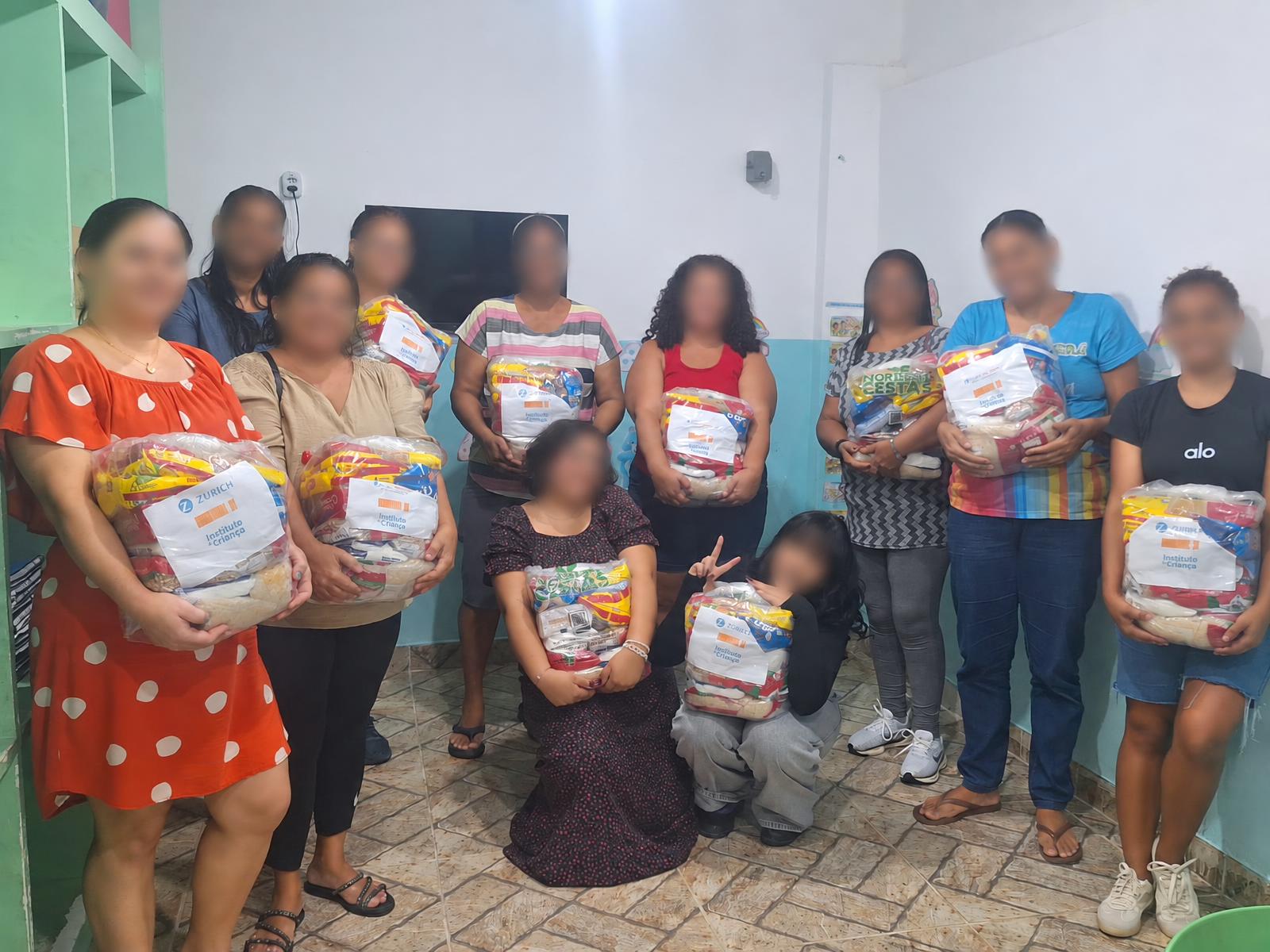 Grupo de pessoas reunidas com cestas de alimentos na instituição.