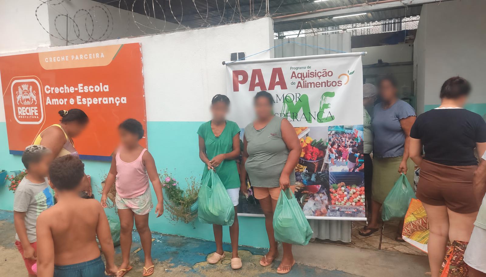 Pessoas com sacolas de alimentos em frente à sede do Amor e Esperança.
