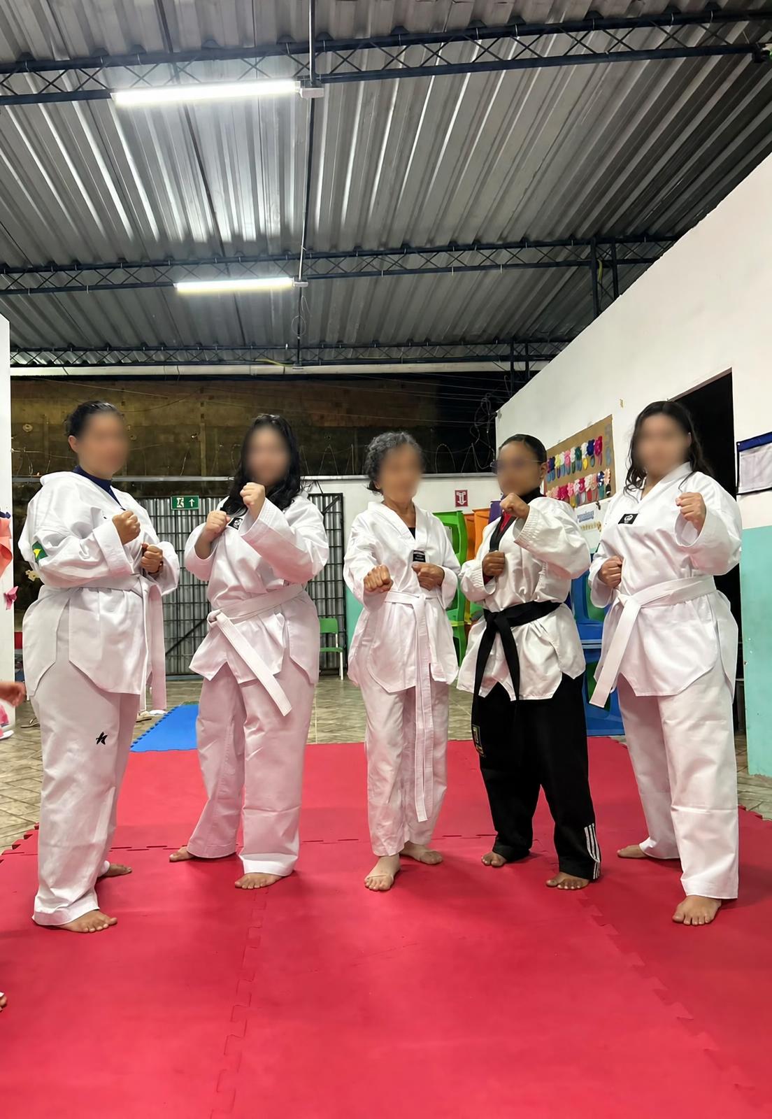 Grupo de adultas com uniformes de taekwondo no tatame.
